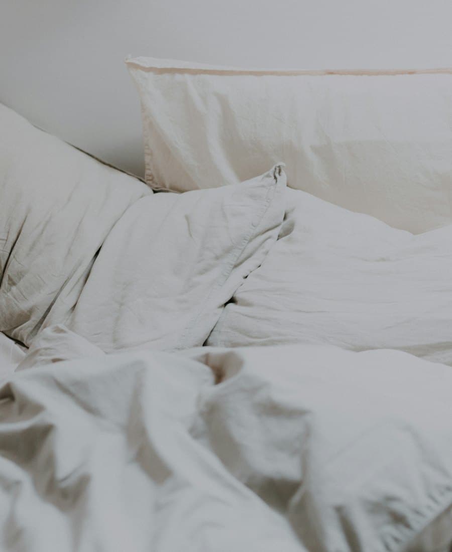A bed made with rumpled white linen sheets